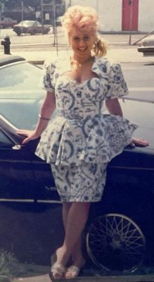 Judy during her younger years, posing for the camera near a car